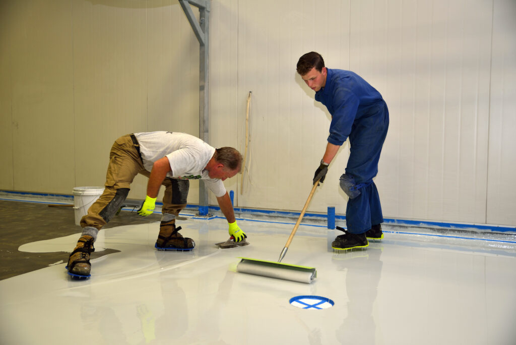 Tradesman applying epoxy product to floor of an industrial building